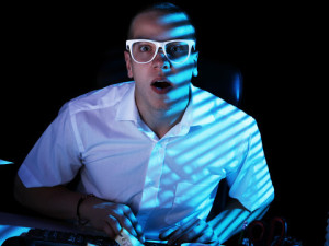 young-man-in-white-shirt-and-glasses-stares-in-shock-at-computer-screen-while-browsing-the-internet